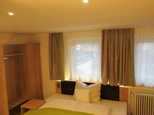 a bedroom with a bed with pillows and a window at Hotel Alp Inn - Chiemgaukarte inclusive in Ruhpolding