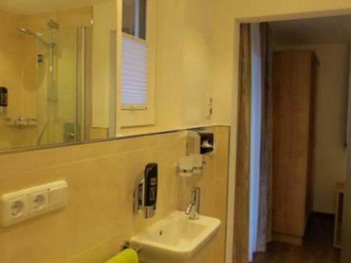 a bathroom with a sink and a mirror at Hotel Alp Inn - Chiemgaukarte inclusive in Ruhpolding