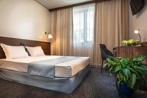 a hotel room with a large bed and a plant at Uniqato Hotel in Stara Zagora
