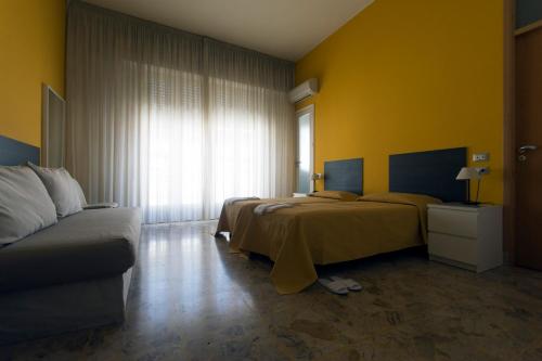ヴィットーリアにあるB&B Artemisiaのベッド2台とソファが備わるホテルルームです。