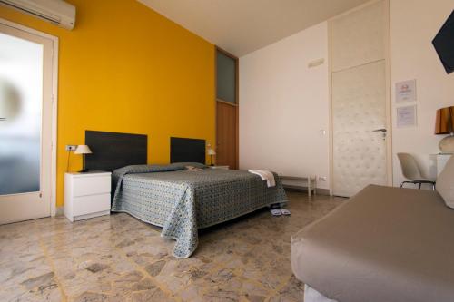 1 dormitorio con cama y pared amarilla en B&B Artemisia en Vittoria