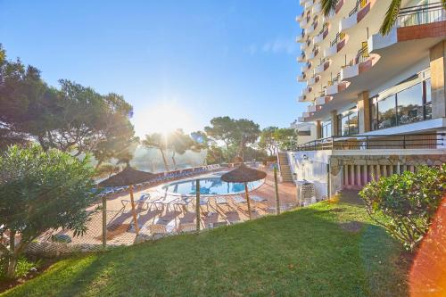 a pool with chairs and umbrellas next to a building at Cabot Cala Ferrera in Cala d´Or