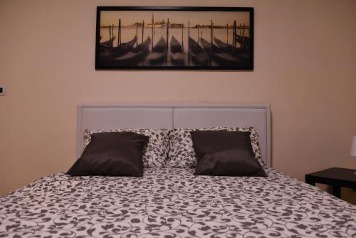 a bed with two pillows and a picture on the wall at 4YOU APARTMENTS - PONTI ROMANI in Padova