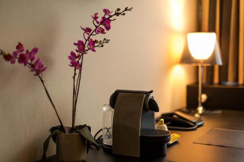 a desk with a phone and purple flowers on it at Hotel Royal in De Panne