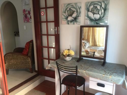 a room with a mirror and a table with a chair at Arum Field Accommodation in Table View