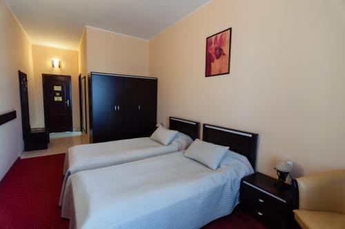 a hotel room with two beds and a chair at Hotel Magnus Galati in Galaţi