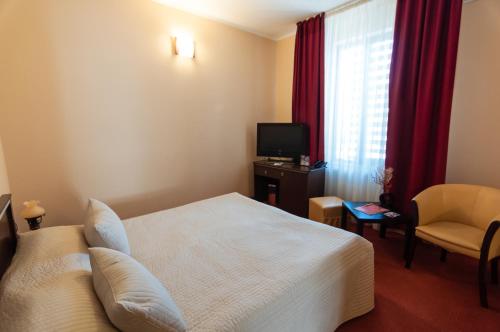 a hotel room with a bed and a chair and a television at Hotel Magnus Galati in Galaţi