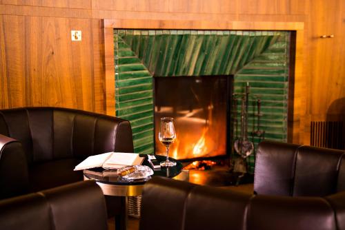 a table with a glass of wine and a fireplace at Hotel Waldhaus Sils in Sils Maria