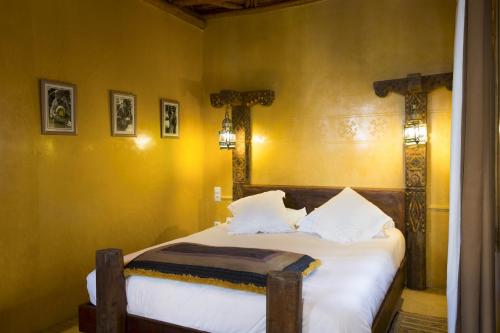 a bedroom with a bed with white sheets and a mirror at Riad Chbanate in Essaouira