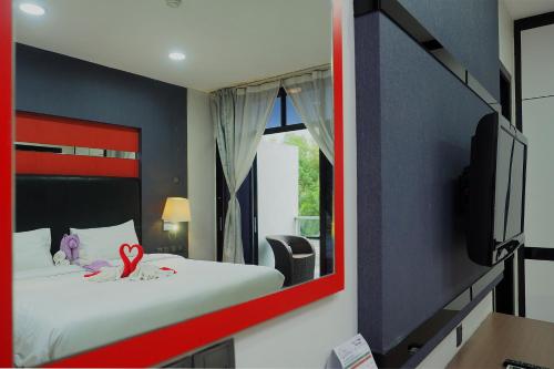 a bedroom with a bed with a red framed mirror at The Centro Hotel & Residence By Orchardz in Batam Center