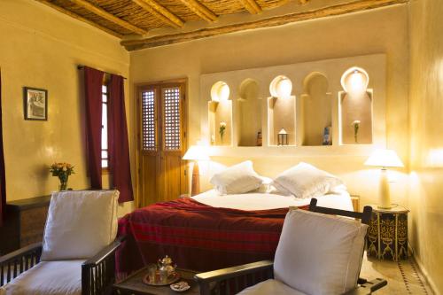 a bedroom with a bed and two chairs at Riad Chbanate in Essaouira