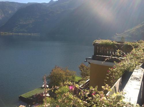 a view of a lake from a house with flowers at Seehotel Grüner Baum in Hallstatt