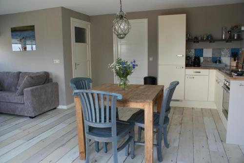 a kitchen and dining room with a wooden table and chairs at Gastenverblijf De Natureluur in Noorden