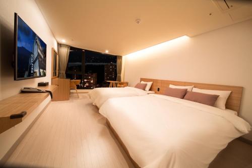 a hotel room with two beds and a television at Pino Hotel in Seogwipo