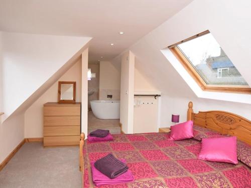 1 dormitorio con 1 cama grande con almohadas rosas en Mallows Byre, en Sherborne