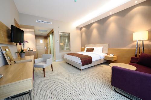 a hotel room with a bed and a couch at Ramada by Wyndham Podgorica in Podgorica