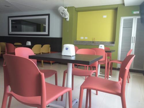 a dining room with tables and red chairs at Hotel 56 Avenue Plaza in Barranquilla