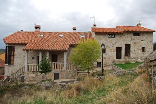 an old stone house with a red roof at Alojamientos El Castillo in El Berrueco