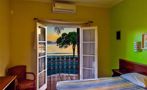 a bedroom with a bed and a sliding glass door at Hotel Villa Di Rimini in Ubatuba