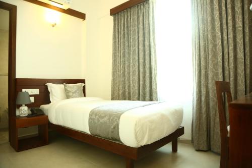 a bedroom with a bed and a large window at Niko Hotels in Cochin