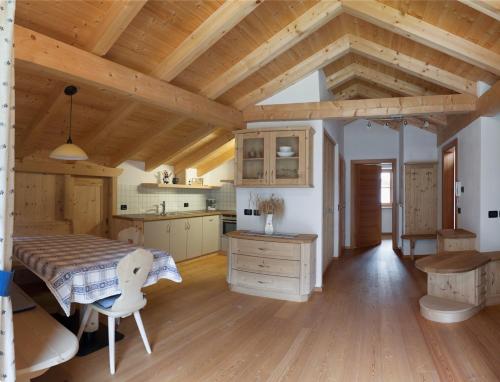 a large kitchen with wooden ceilings and a table at Ciasa Medalghes in San Martino in Badia