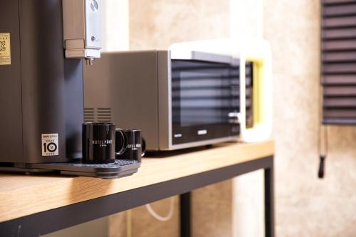 a microwave and two coffee cups on a counter at Pino Hotel in Seogwipo