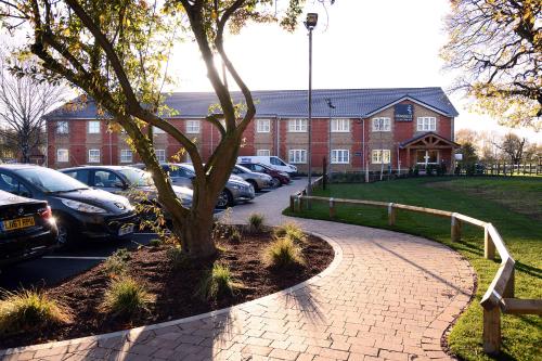 a brick building with cars parked in a parking lot at Woodcocks, Lincoln by Marston's Inns in Lincoln