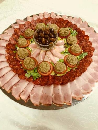 ein Kuchen mit Schinken und Oliven auf einer Platte in der Unterkunft Mari Vila Hotel in Bukarest