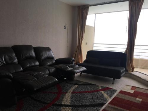 a living room with a leather couch and a chair at Duplex Jacuzzi San Alfonso del Mar in Algarrobo