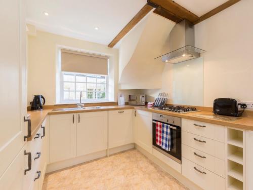 a kitchen with white cabinets and a stove top oven at George III in Winchcombe