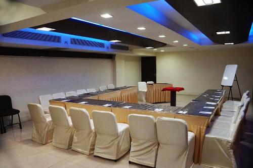 a conference room with a long table and white chairs at SilverCloud Hotel and Banquets in Ahmedabad
