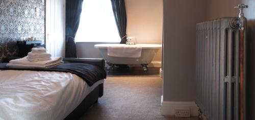 a bedroom with a bed and a tub and a sink at The Windmill Inn - Whitby in Whitby
