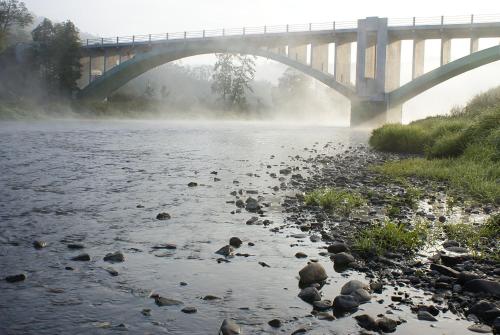 a bridge over a river with rocks in the water at Hotel Berounka in Liblín