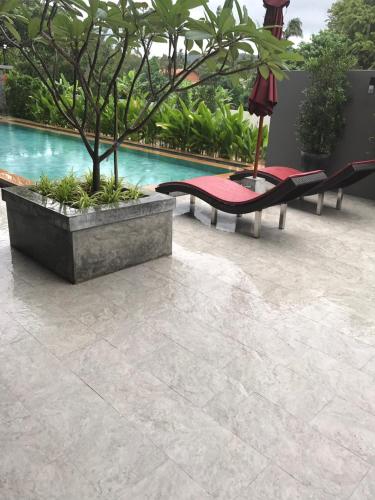 a patio with two benches and a tree next to a pool at Amarina Green in Lamai