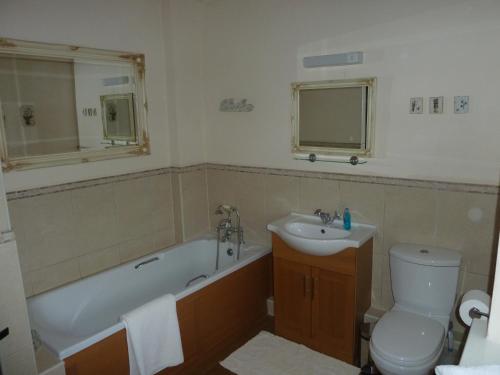 y baño con bañera, lavabo y aseo. en Royds Hall Cottage en Keighley