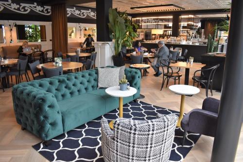 a green couch in a restaurant with tables and chairs at Hotel Theater Figi in Zeist