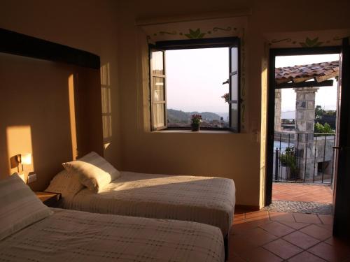 two beds in a room with a window and a balcony at Hotel Boutique La Casona de Don Porfirio in Jonotla