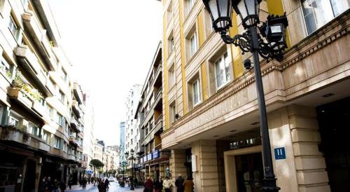 a street with people walking down a street with buildings at Hotel Clarin in Oviedo