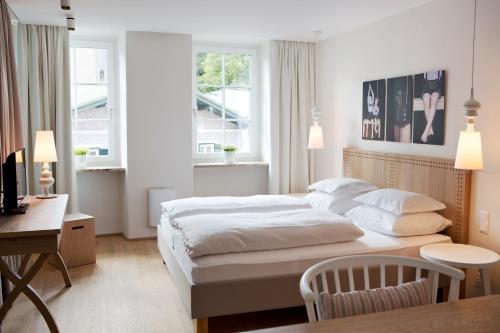 a bedroom with a bed and a desk and windows at Genießerhotel Döllerer in Golling an der Salzach