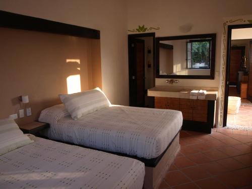 a bedroom with two beds and a sink and a mirror at Hotel Boutique La Casona de Don Porfirio in Jonotla
