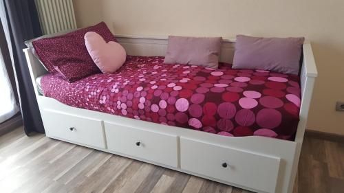 a bed with purple and pink pillows on it at Cuorematto in Poggiridenti