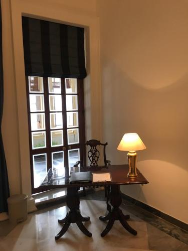 a table with a lamp in front of a window at The Harrington Residency in Kolkata