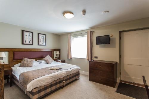 Habitación de hotel con cama y TV en The Plough Inn & Restaurant en Congleton
