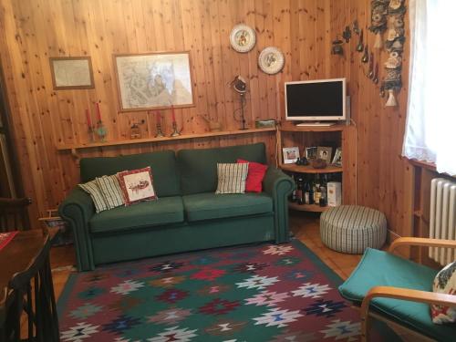 uma sala de estar com um sofá verde e uma televisão em Casa Alagna em Alagna Valsesia