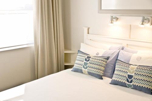 a bedroom with a bed with blue and white pillows at South Point Guest Lodge in Agulhas