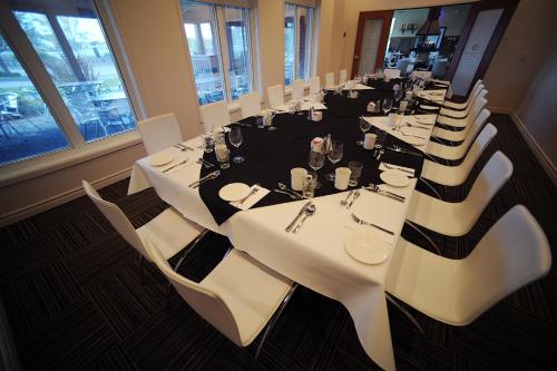 a long table with white tables and chairs in a room at Hôtel Énergie Shawinigan in Shawinigan