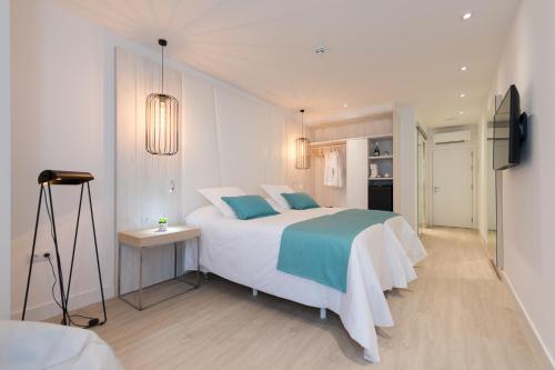 a white bedroom with a large bed with blue pillows at HC Luxe in Vecindario