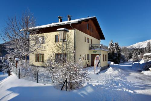a house in the snow with a fence in front at Pension Klug Adults only - DorfResort Mitterbach in Mitterbach