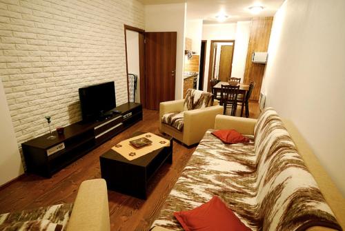 a living room with a couch and a tv at Ski & Sun Wellness Apartments in Liptovský Mikuláš