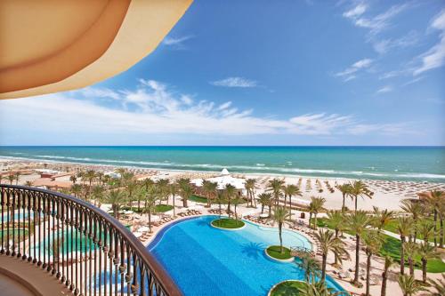 a view of the beach from the balcony of a resort at Mövenpick Resort & Marine Spa Sousse in Sousse